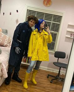 a man and woman standing next to each other in front of a mirror with yellow raincoats on