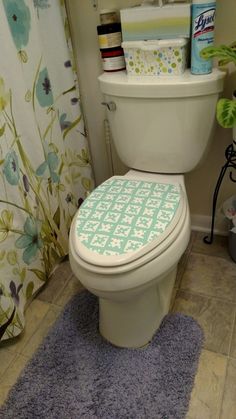 a white toilet sitting in a bathroom next to a blue rug and shower curtain with flowers on it