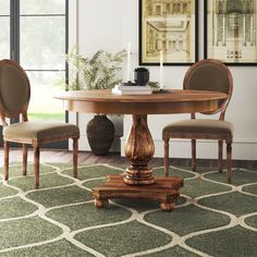 a dining room table with four chairs and a rug in front of the table,