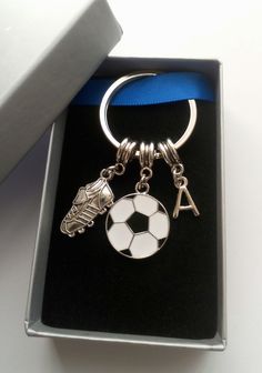 a silver keychain with a soccer ball and shoes on it in a box