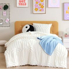 a bed with white comforter and pillows on top of it next to pictures hanging on the wall