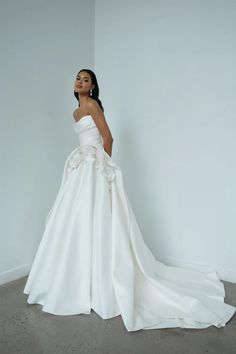 a woman in a white wedding dress standing against a wall