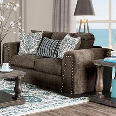 a living room filled with furniture and a large window next to the ocean in front of it