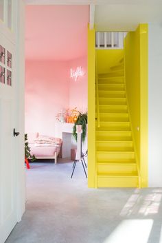 an open door leading to a pink and white room with yellow stairs in the center