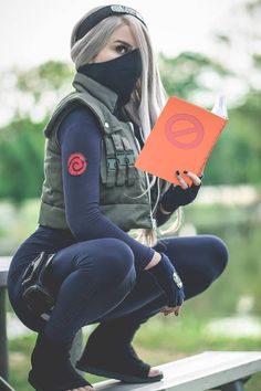 a woman wearing a mask sitting on a bench with an orange book in her hand