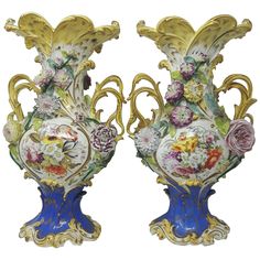 two decorative vases with flowers on them sitting next to each other in front of a white background