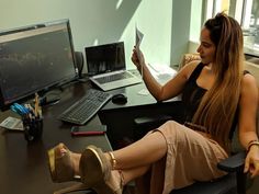 a woman sitting at a desk with her feet up in the air while reading a book