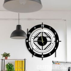 a black and white clock hanging on the wall next to a desk in an office