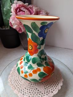 a flowered vase sitting on top of a glass table next to a potted plant