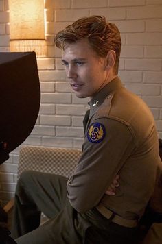 a man in uniform sitting next to a television monitor