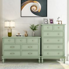 a green dresser sitting next to a painting on the wall