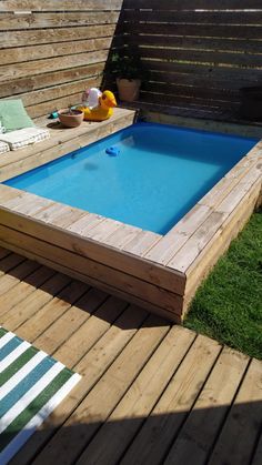 a wooden deck with an above ground swimming pool in the middle and lawn area behind it