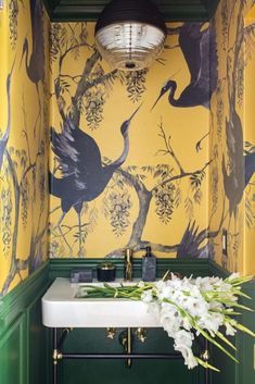 a bathroom with yellow and green wallpaper has a white sink in front of it