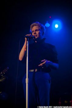 a man standing in front of a microphone with his hand on the mic and singing