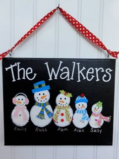 a black sign that says the walkers with four snowmen in different hats and scarves