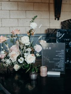 a vase with flowers on a table next to a bar sign and candlesticks