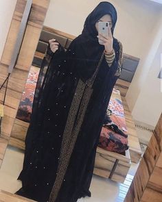 a woman taking a selfie in front of a mirror wearing a black outfit and holding a cell phone