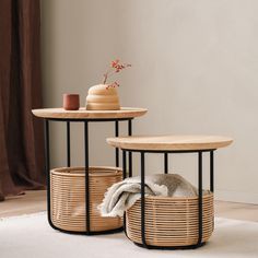 two round tables with baskets on them and a vase in the middle, sitting on a white rug