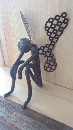 a metal sculpture of a man holding a key on top of a wooden table next to a door