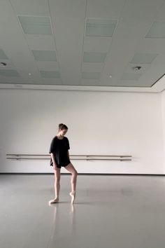 a person standing on one leg in an empty room with white walls and flooring