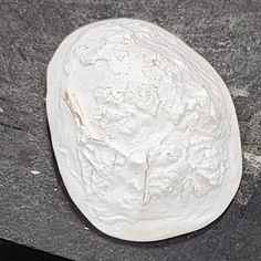 a piece of white pottery sitting on top of a black table next to a knife