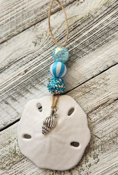 a white sand dollar with blue and silver beads hanging from it's side on a string