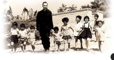 an old black and white photo of a man standing in front of a group of children