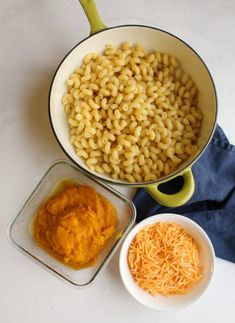 macaroni and cheese in a pan with two bowls on the table next to it