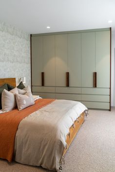 a large bed sitting next to a wall with cabinets on it's sides in a bedroom