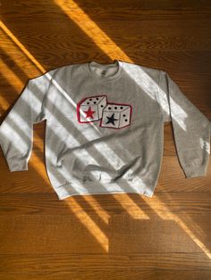 a sweatshirt with two dice on it sitting on a wooden floor