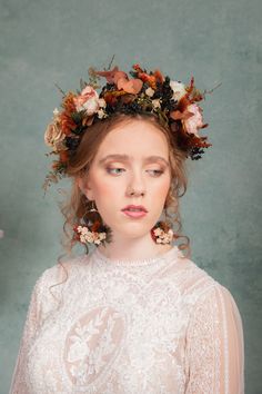 a woman with flowers in her hair wearing a white dress and flower crown on her head