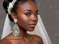 a woman in a wedding dress wearing a bridal veil and diamond earrings on her head