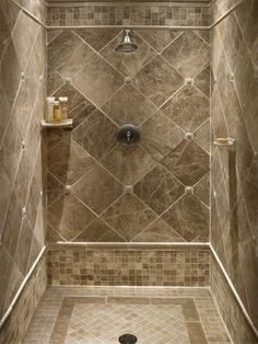 a bathroom shower with brown tile on the walls and floor, is shown in an instagram