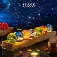 an array of glass orbs sitting on top of a wooden stand in front of a night sky filled with stars