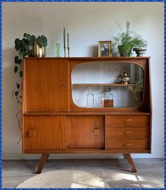 a wooden cabinet with glass doors and plants on top