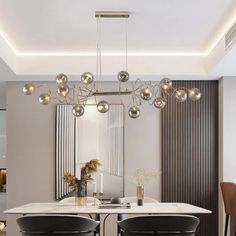 a modern dining room with black chairs and a white marble table surrounded by hanging lights