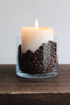 a lit candle sitting on top of a table filled with coffee beans and cinnamons