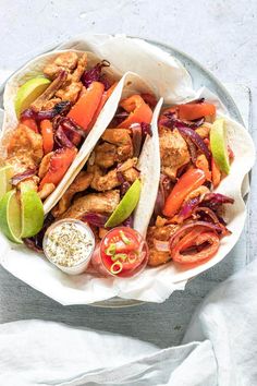 two tacos with chicken, peppers and onions on a plate