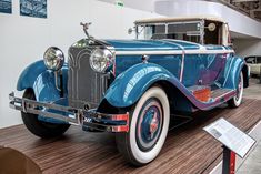 an antique blue car on display in a museum