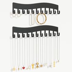 two black wall mounted jewelry racks with rings and necklaces hanging from the hooks on them