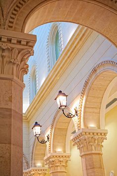 the inside of a building with arches and lamps on either side of it's pillars