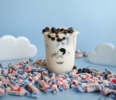 a cup filled with milk and chocolate chips on top of a blue table next to clouds