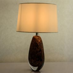 a lamp that is on top of a table with a white shade over the base