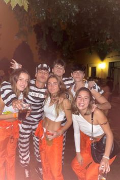 a group of people dressed up in jail clothes posing for a photo with one person holding a drink