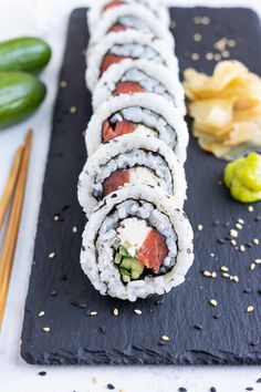 sushi rolls with cucumber and sesame seeds on a black slate platter