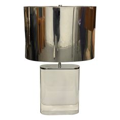 a lamp that is sitting on top of a glass table with a silver shade over it