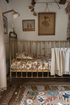 a small crib in a room with pictures on the wall and a rug on the floor