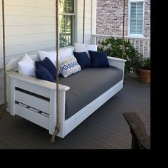 a white porch swing with blue and white pillows