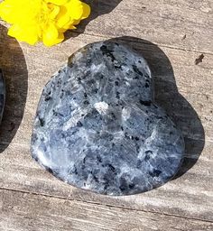 two rocks sitting on top of a wooden table next to yellow daffodils