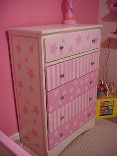 a pink and white dresser with stars painted on the drawers in a child's bedroom